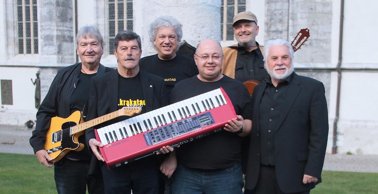 Sechs Musiker mit Instrumenten vor der Kirche